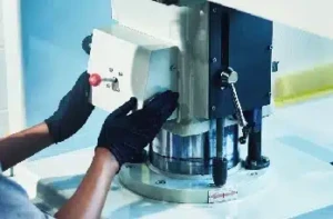 die cutting Gloved technician operating a precision die cutting machine to shape custom plastic components for manufacturing.